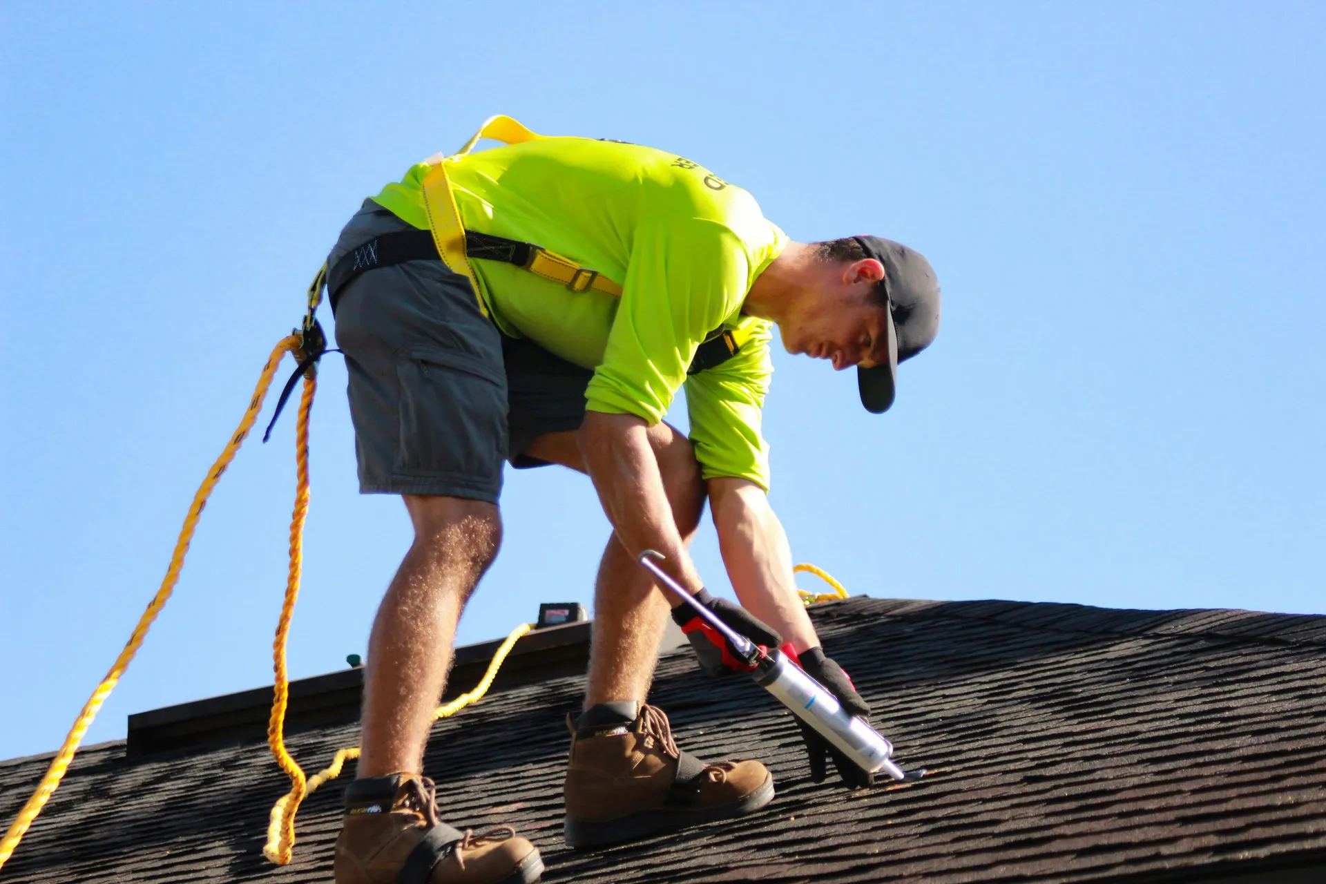 A professional roofer using a heat welder to repair the seam on a white commercial TPO roof.