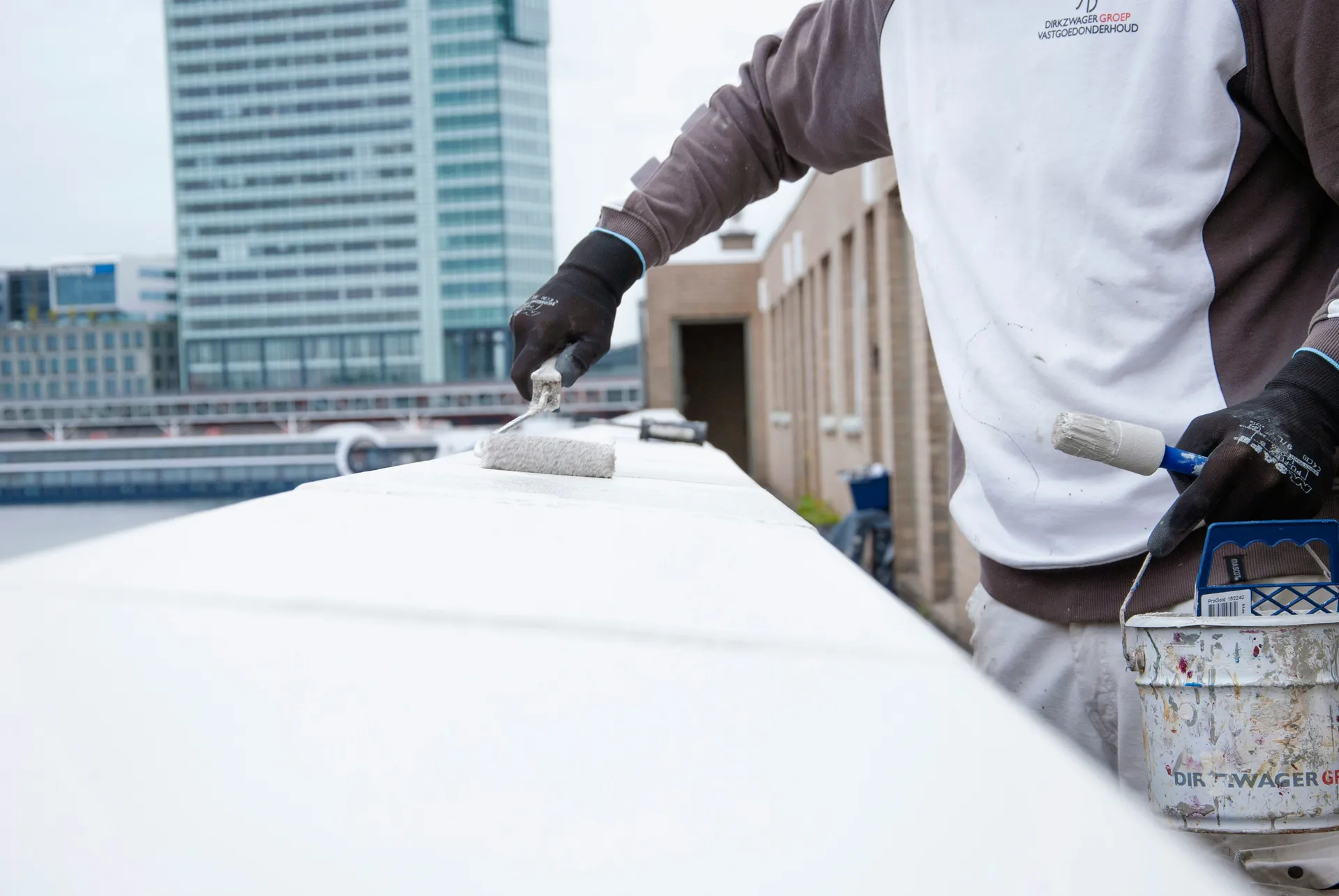 A professional applying a white liquid waterproofing membrane to a flat roof with a roller.