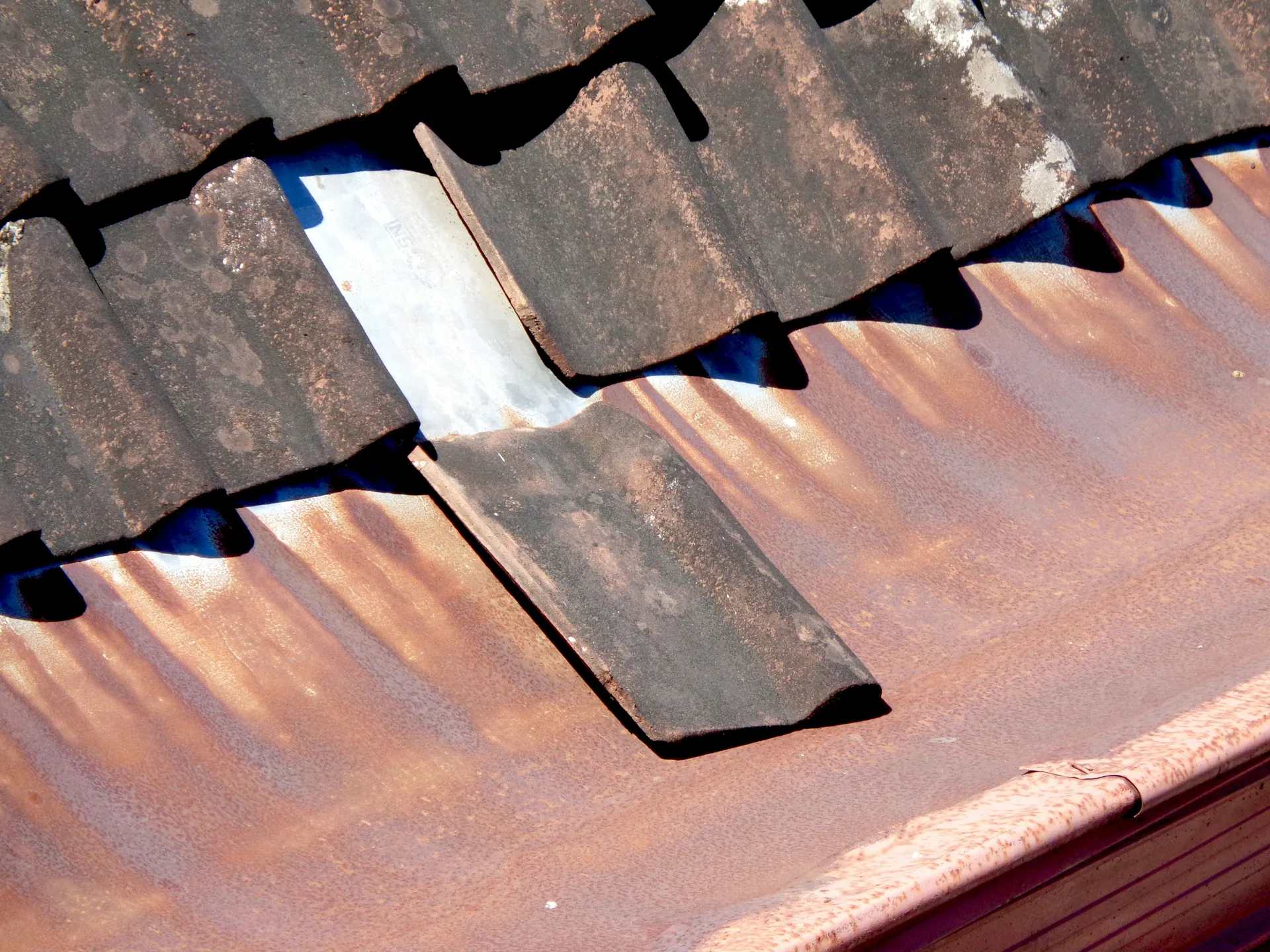A rusted metal roofing cop with cracked sealant, showing clear signs of water intrusion risk.