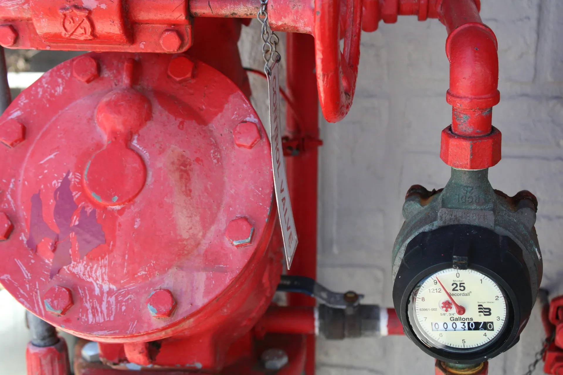 A close-up of a main gas shutoff valve located next to a home's gas meter.