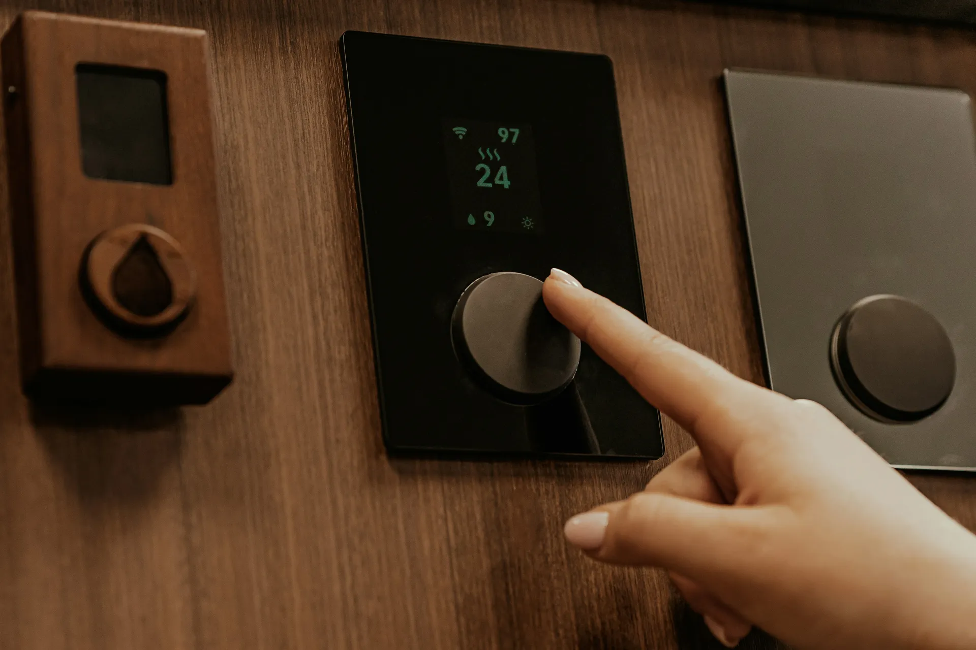 A person's hand adjusting a modern digital thermostat on a wall, checking the settings because the heat is not working.