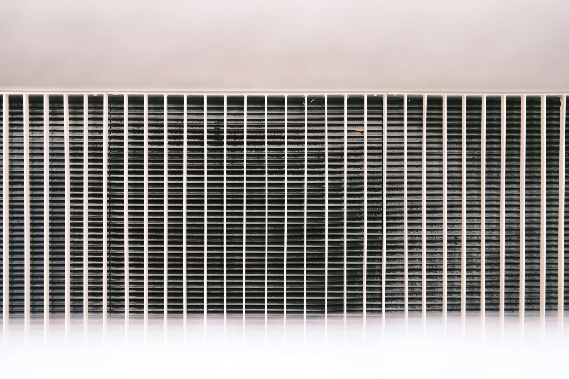 A person's hands sliding a clean, new air filter into the HVAC air handler slot.