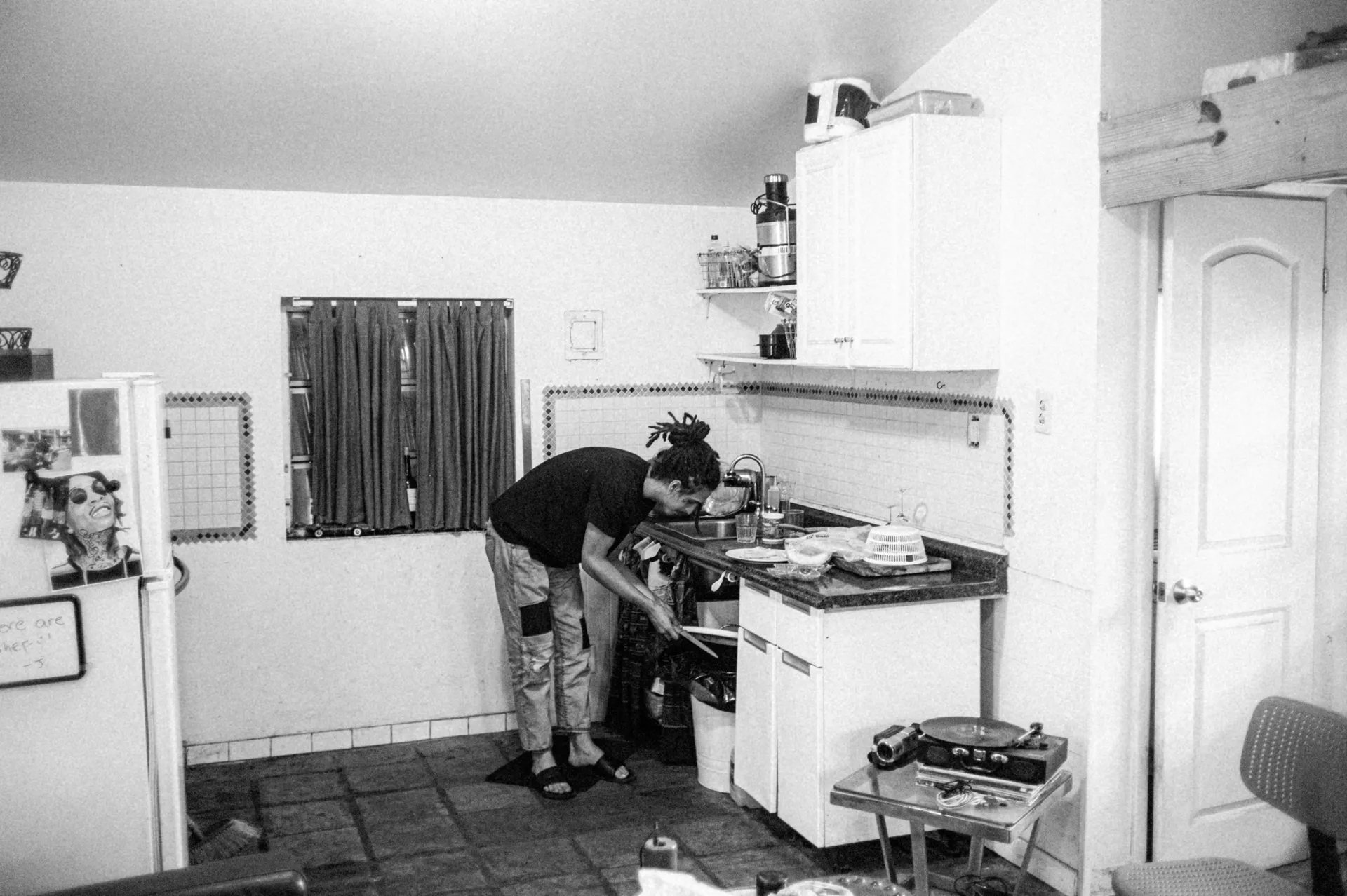 A plumber's hands are shown installing a new garbage disposal under a stainless steel kitchen sink.